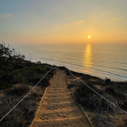 steps leading to a beach with a sunset